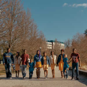 outdoor portrait of a family of 10 walking side by side towards the camera looking at different directions